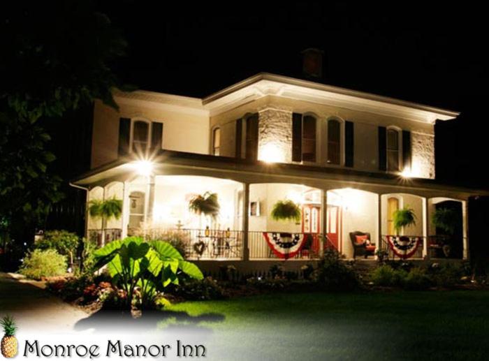 Une grande maison blanche éclairée la nuit dans l'établissement Monroe Manor Inn, à South Haven