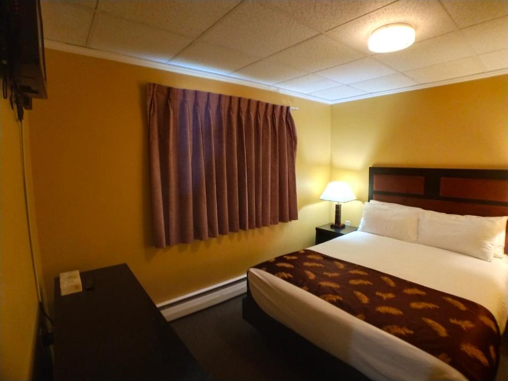 a hotel room with a bed and a window at Alpine Inn & Suites in Revelstoke
