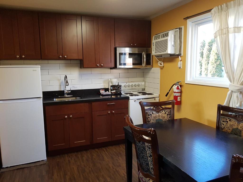 a kitchen with a white refrigerator and a table at Alpine Inn & Suites in Revelstoke
