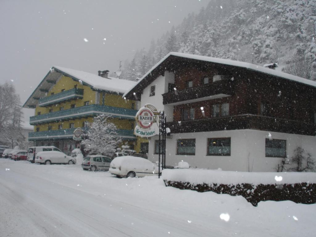 ein schneebedecktes Gebäude mit Autos im Schnee in der Unterkunft Gasthof Schaber in Pettnau