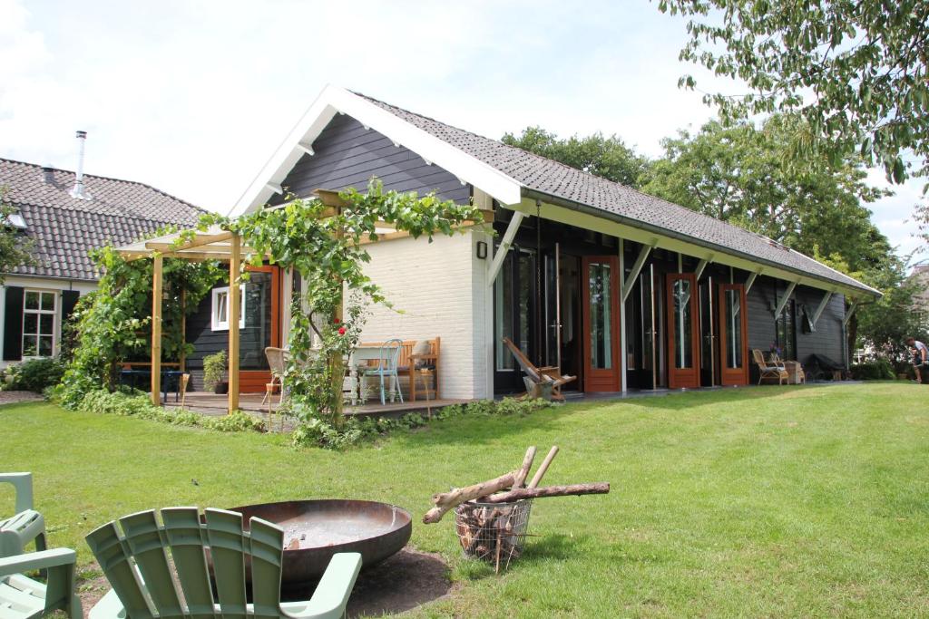 une maison avec une cour dotée d'une chaise verte dans l'établissement Familiehuis De Betuwe met prive kunstgras tennisbaan en sauna, à Erichem