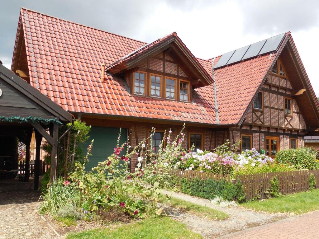 Ferienwohnung-Kribitz-Hodenhagen في هودنهاغن: منزل بسقف احمر وبعض الزهور