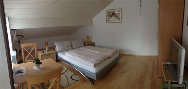 a small bedroom with a bed and a table at Ferienwohnung Mühlbach in Isny im Allgäu