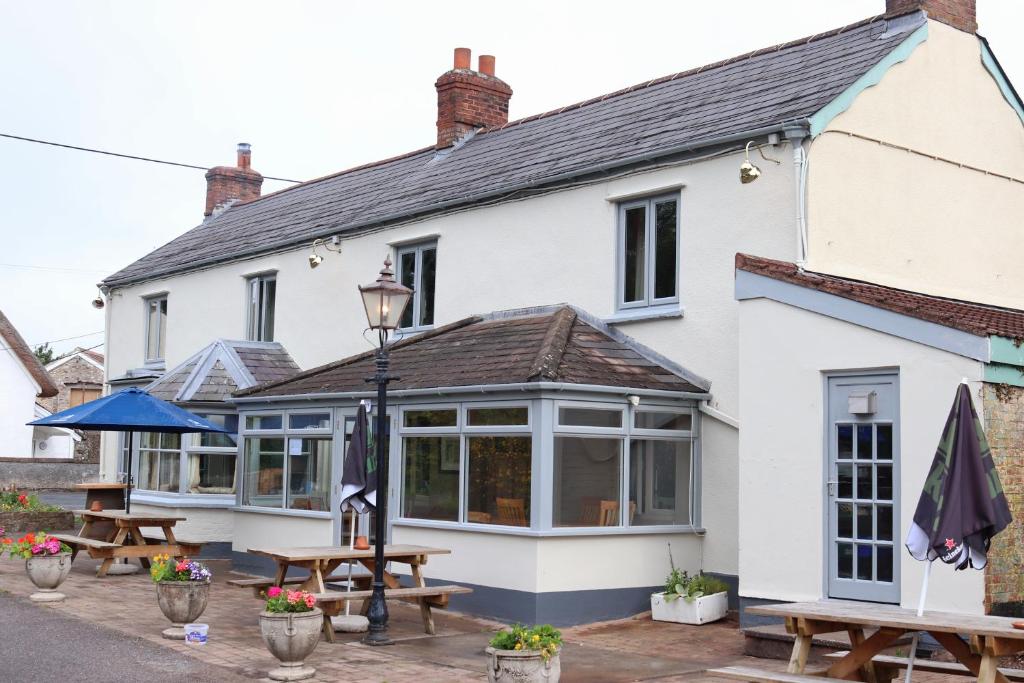 un edificio blanco con mesas de picnic delante en Culm Valley Inn en Culmstock