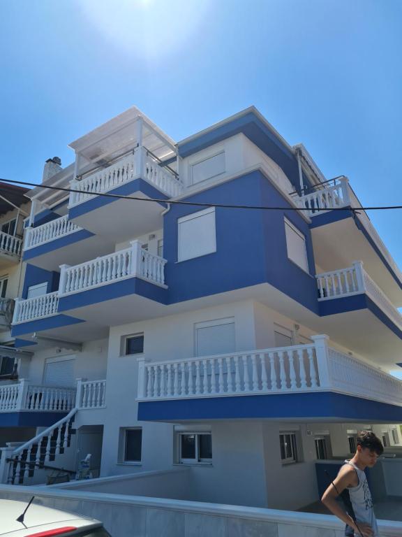 a boy walking in front of a blue building at Apartments Nera Paralia-Apartment with sea view in Paralia Katerinis