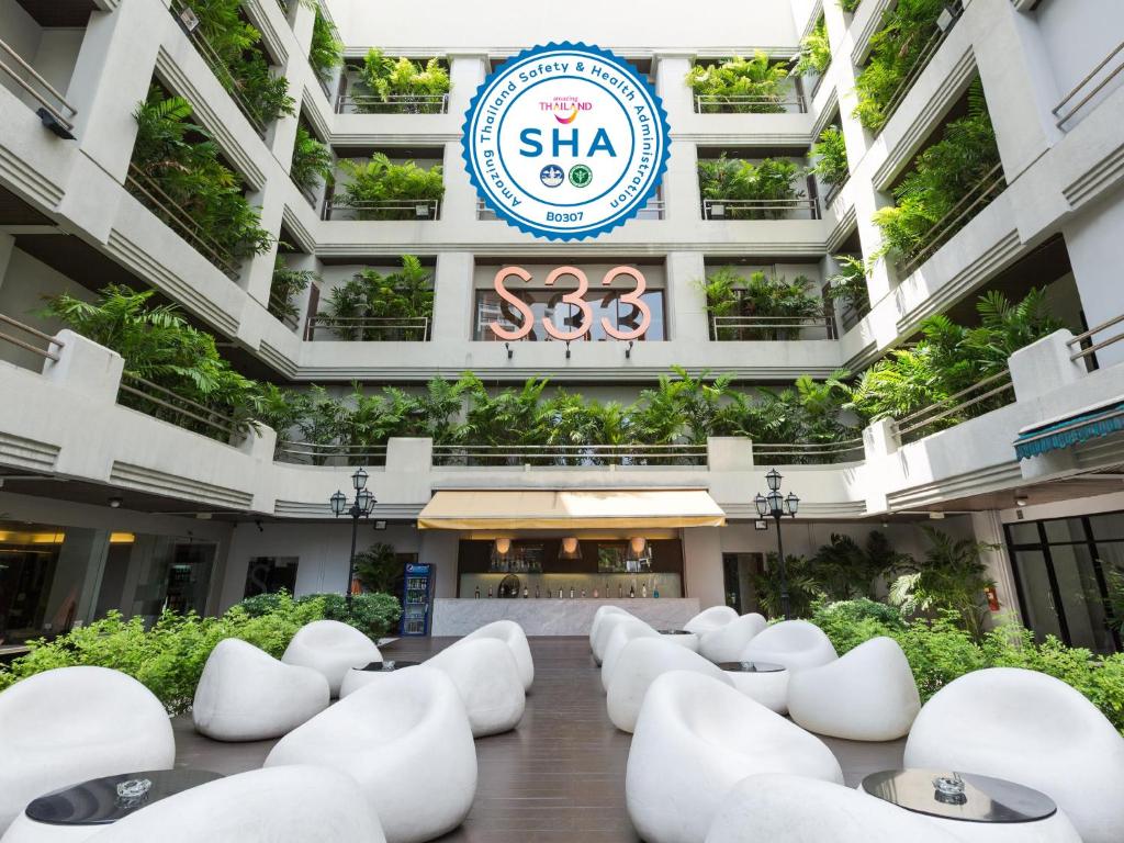 budynek z białymi krzesłami przed nim w obiekcie S33 Compact Sukhumvit Hotel w mieście Bangkok
