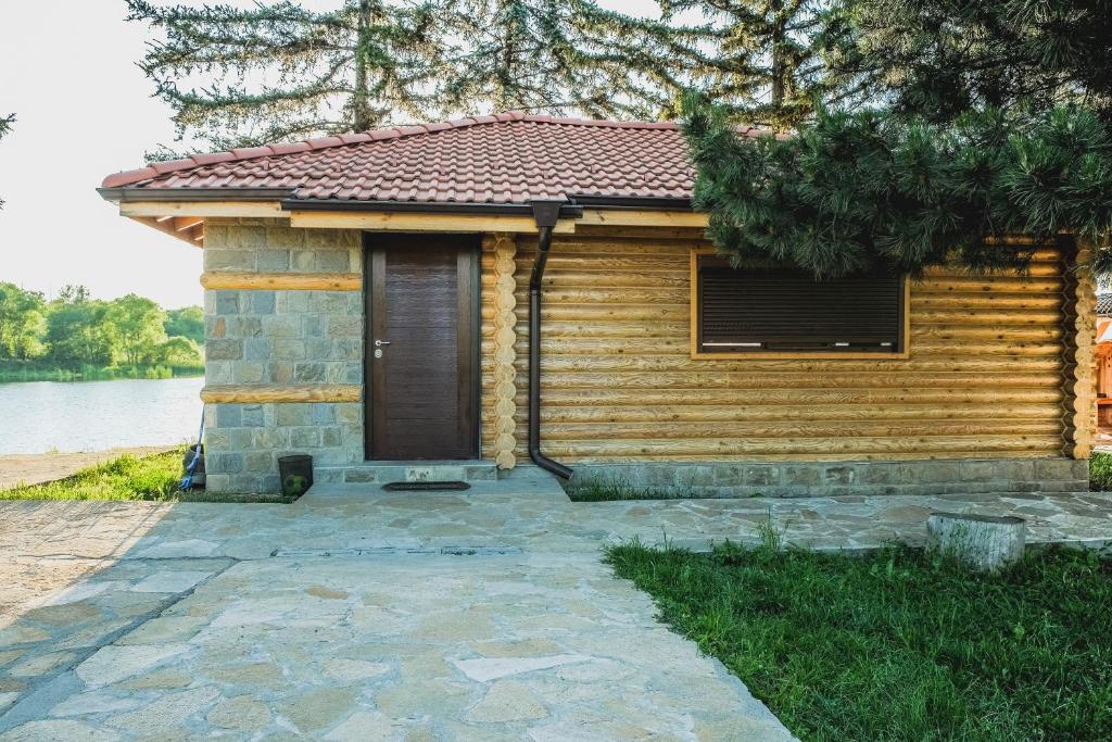 een houten hut met een deur voor een meer bij Къща за Гости in Ivanyane