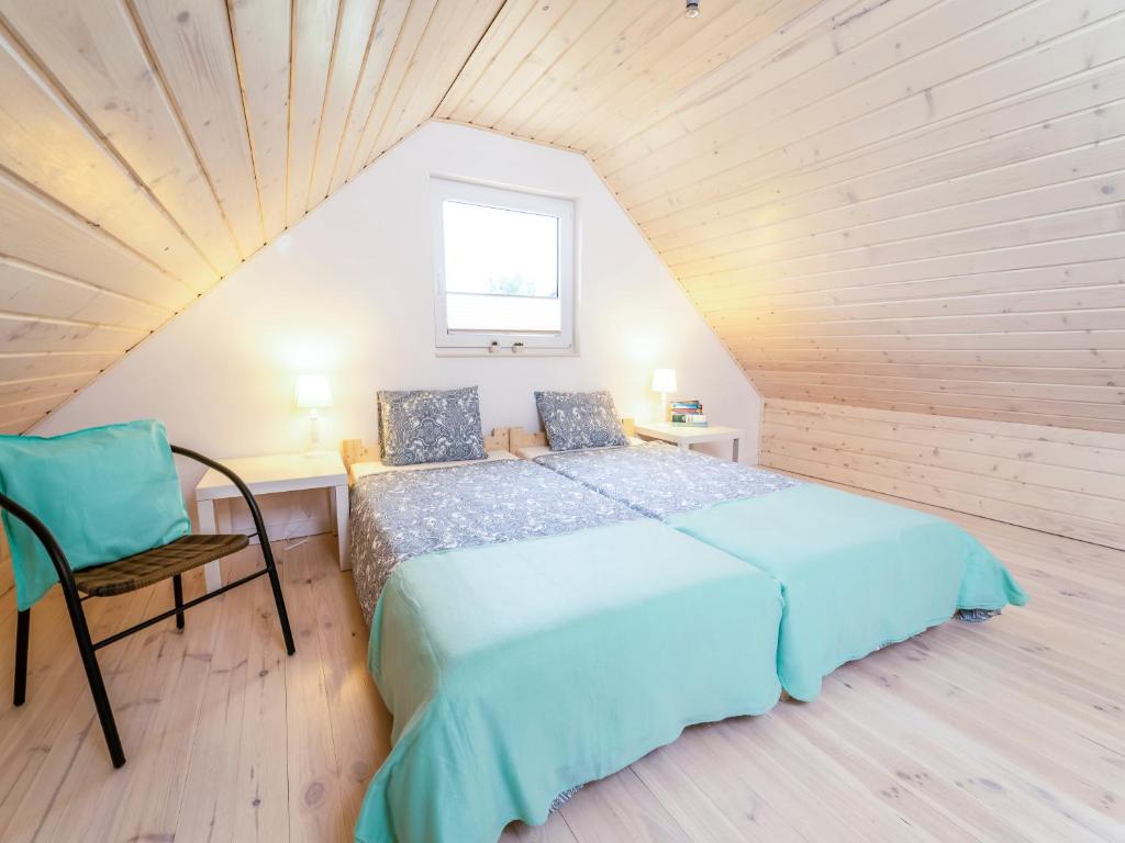 a bedroom with a bed and a chair in a attic at Kolory Mazur in Stare Jabłonki