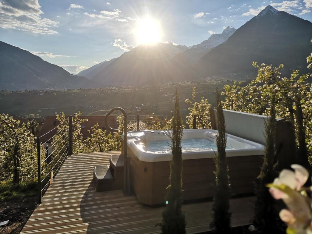 a hot tub on a deck with a view of mountains at Active B&B Prairerhof in Schenna