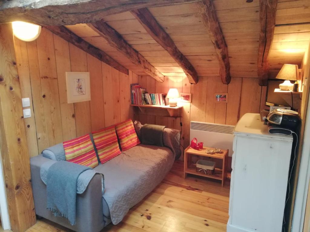 - un salon avec un canapé dans une chambre dotée de murs en bois dans l'établissement Arcogite, à Vicdessos