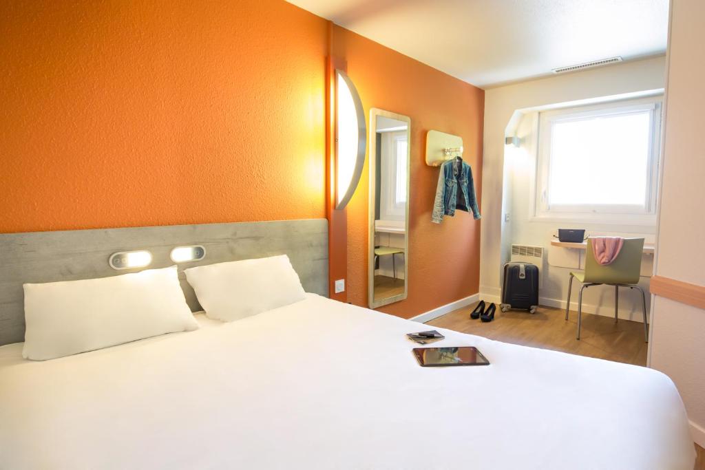 a bedroom with a large white bed and a desk at ibis budget Vienne Sud in Vienne