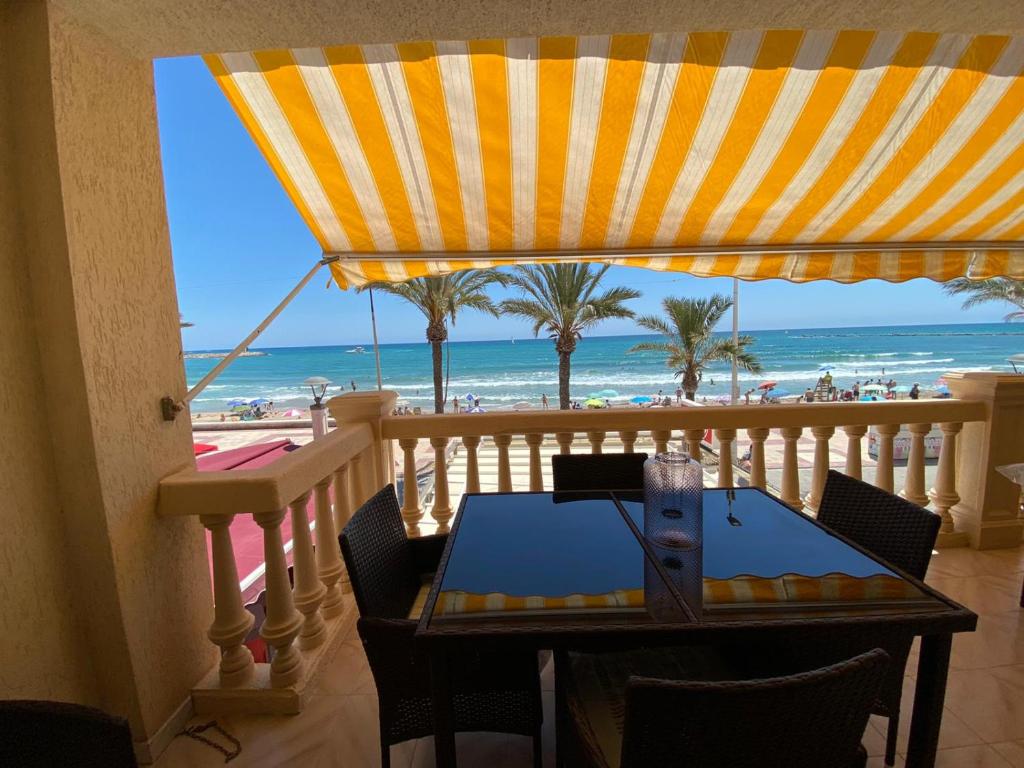 een balkon met een tafel en uitzicht op het strand bij Apartamento frente al mar en El Campello in El Campello