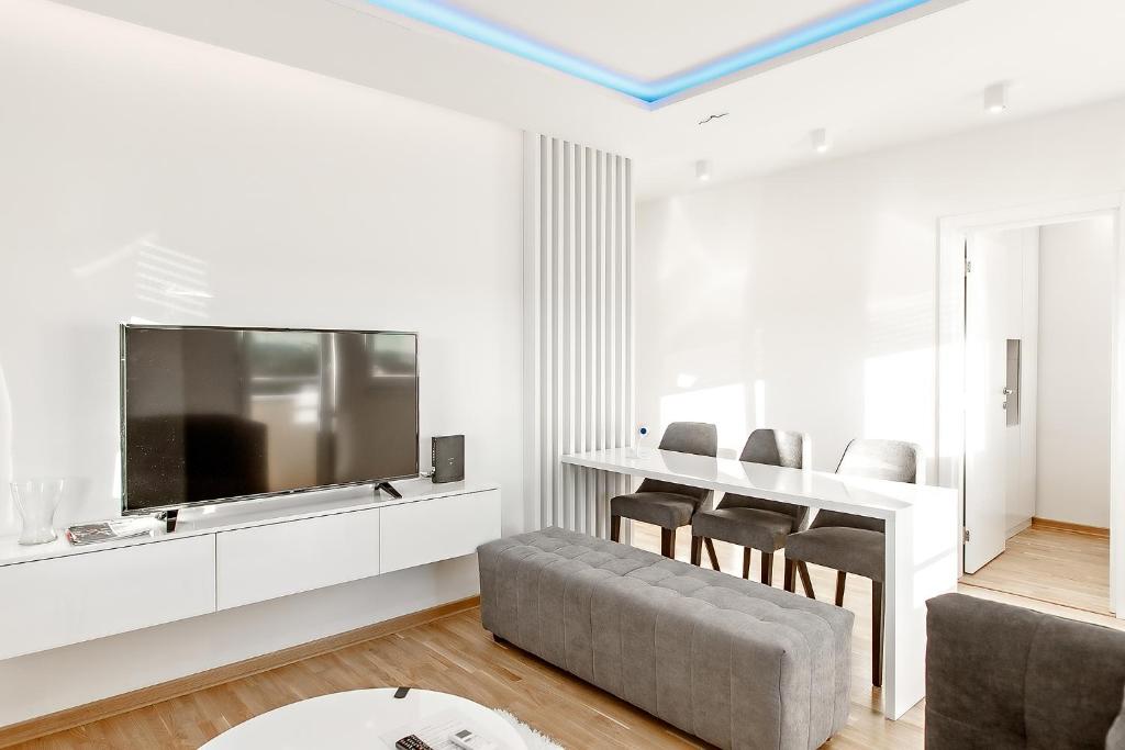 un soggiorno con grande TV e tavolo di White Apartments a Belgrado