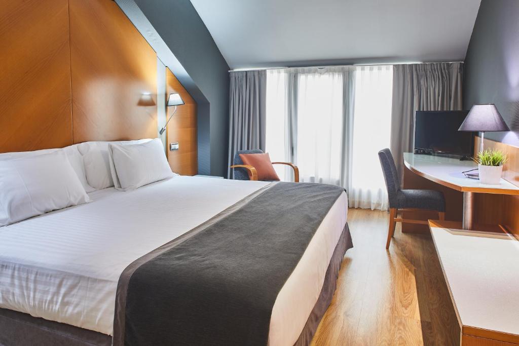 um quarto de hotel com uma cama grande e uma secretária em Silken Juan de Austria em Valladolid
