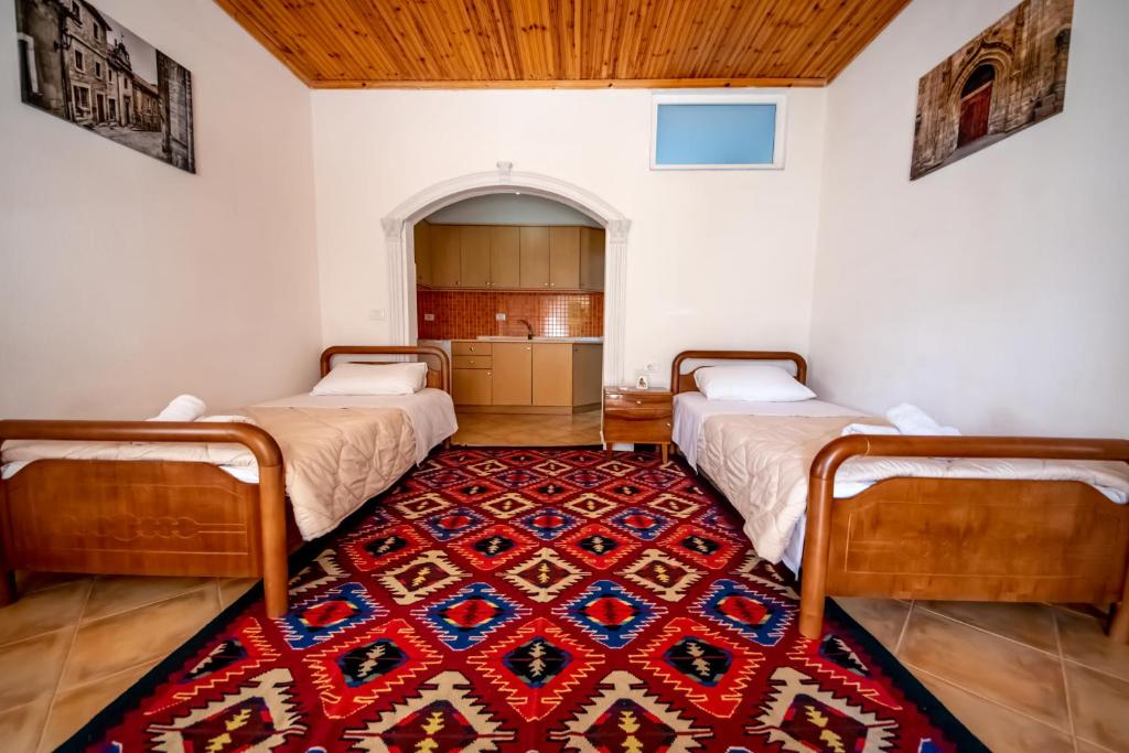 2 camas en una habitación con alfombra roja en Guest House Garden, en Gjirokastra