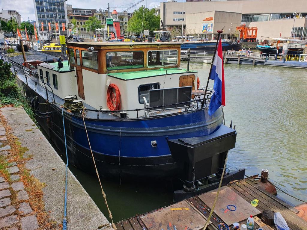 a blue and white boat sitting in the water at Houseboat holiday apartments Rotterdam in Rotterdam