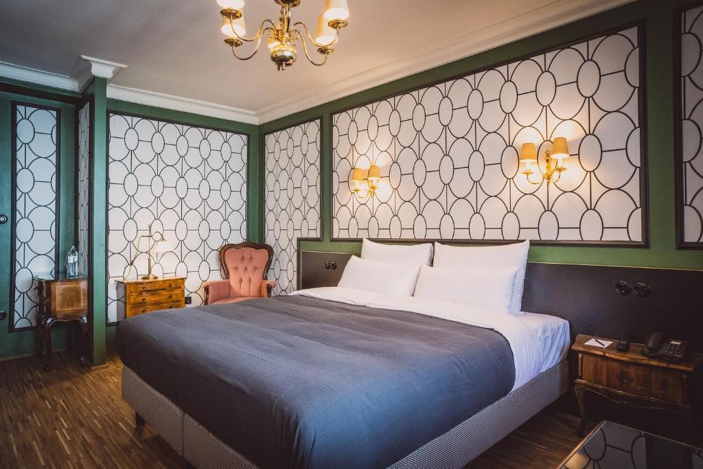 a bedroom with a large bed and a chandelier at HENRI Hotel Wien Siebterbezirk in Vienna