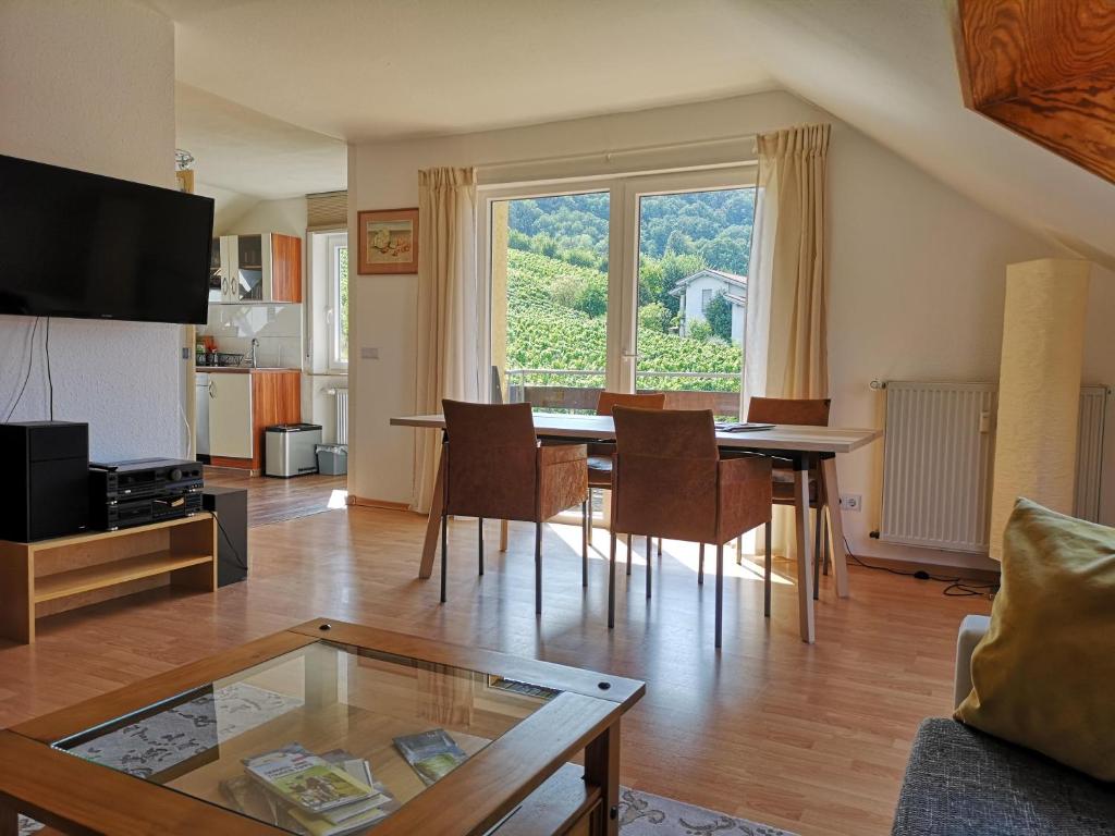 uma sala de estar com uma mesa e cadeiras e uma grande janela em Ferienwohnung "Weinbergblick" im Winzerdorf em Leinsweiler