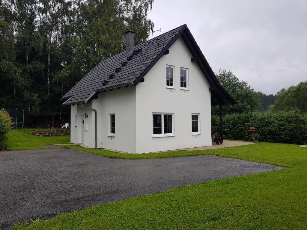 a white house with a black roof on a driveway at Holiday House Tereza in Lipno nad Vltavou