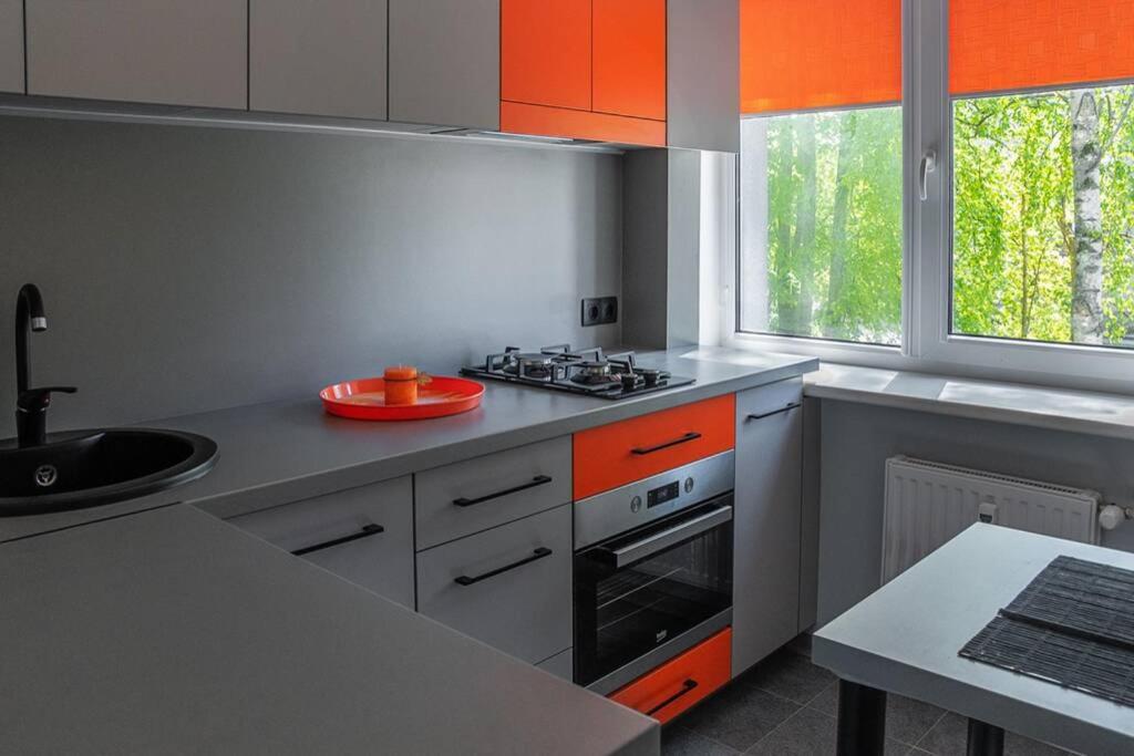 een keuken met oranje kasten en een fornuis met oven bij Jaukus 1.5 kambario butas prie Akropolio. in Klaipėda