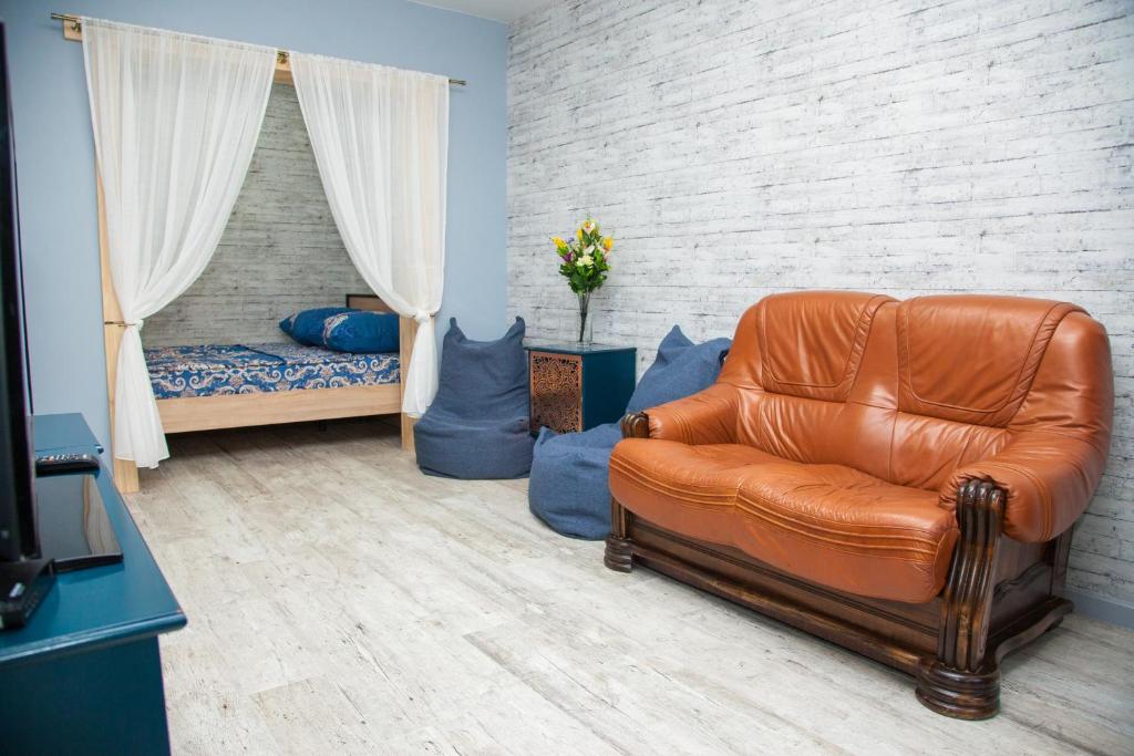 a living room with a leather couch and a bed at Lux apartment on Nezalezhnoi Ukrаiny 39-B near Bulvar Shevchenko in Zaporozhye