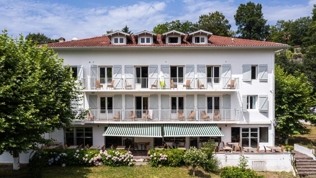 ein großes weißes Gebäude mit rotem Dach in der Unterkunft Hôtel du Pont in Ascain