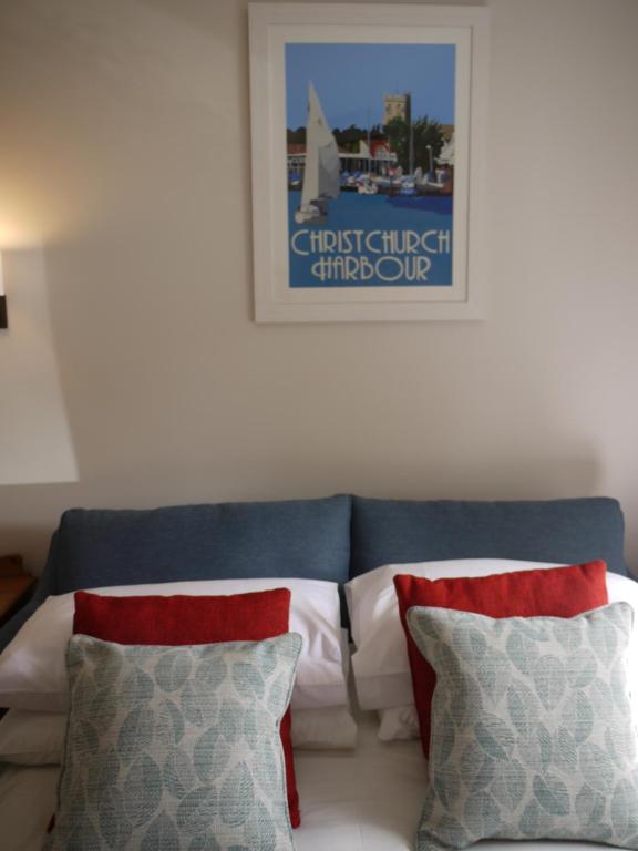 a couch with two pillows and a picture on the wall at Cranborne House in Poole
