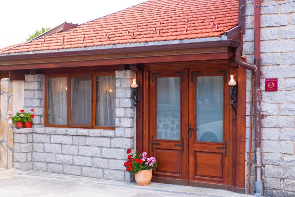 uma casa de tijolos com uma porta de madeira e flores em Grancharova Guest House em Bansko