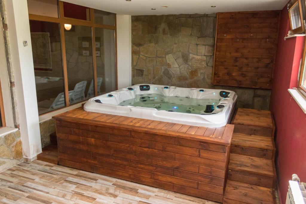 a jacuzzi tub in a room with a stone wall at Hotel Uzunski in Smolyan