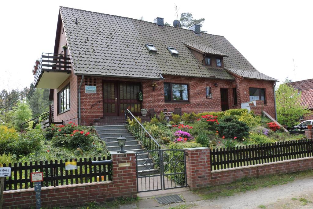 uma casa de tijolos com uma cerca em frente em Gästezimmer Neumair em Undeloh