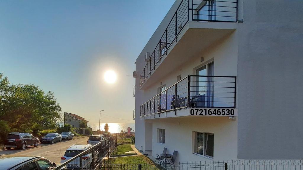 a building with a balcony with cars parked on the street at Vila Tropicana in Eforie Sud