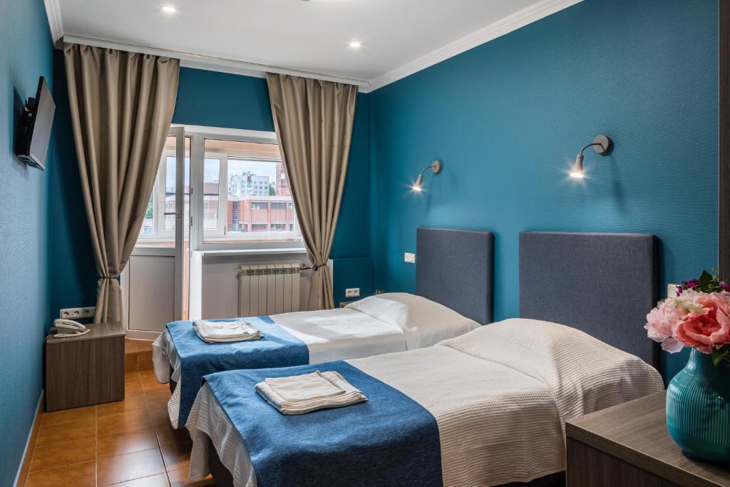 two beds in a room with blue walls at Hotel Luko in Saint Petersburg