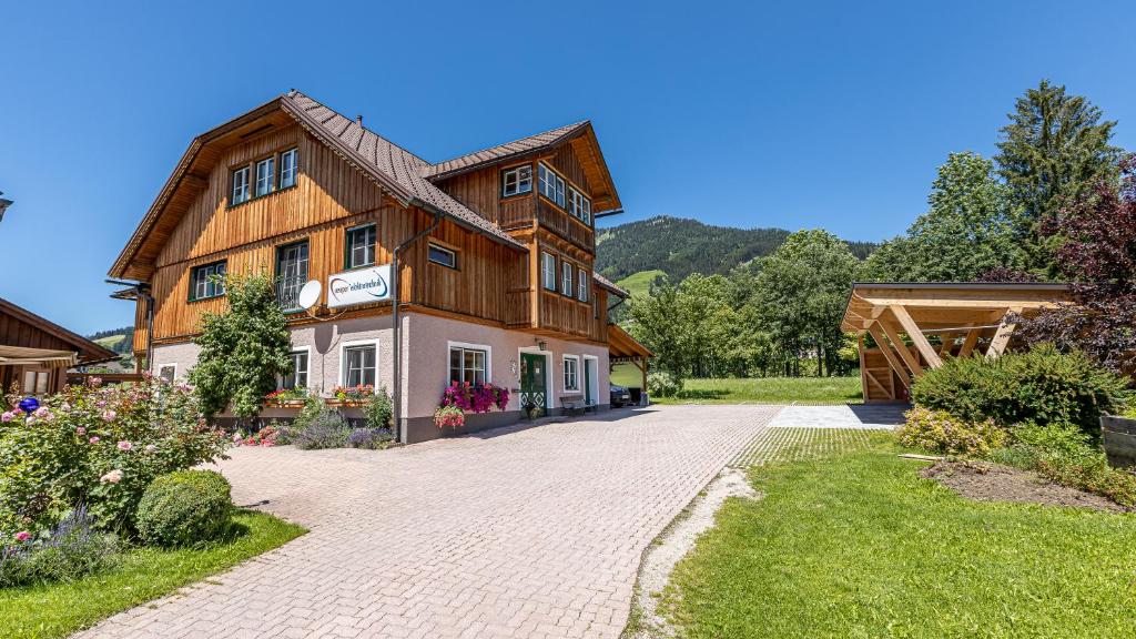 ein großes Holzhaus auf einer Ziegelsteinfahrt in der Unterkunft Ferienwohnung Neuper in Bad Mitterndorf