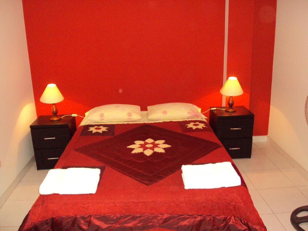 1 dormitorio rojo con 1 cama con colcha roja y 2 lámparas en Nasca Lodge, en Nazca