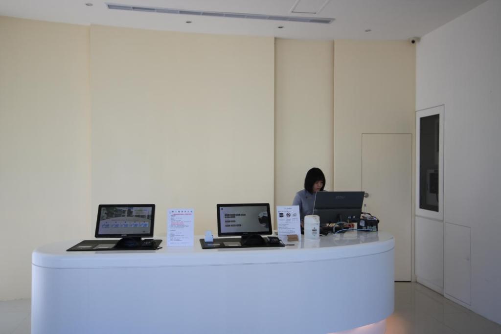 a woman sitting at a counter with two laptops at Hotel Papa Whale-Kaohsiung Formosa Boulevard in Kaohsiung