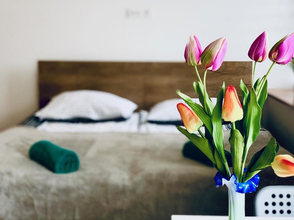 wazon z kwiatami na stole przed łóżkiem w obiekcie Dworcowa 10D w mieście Płock