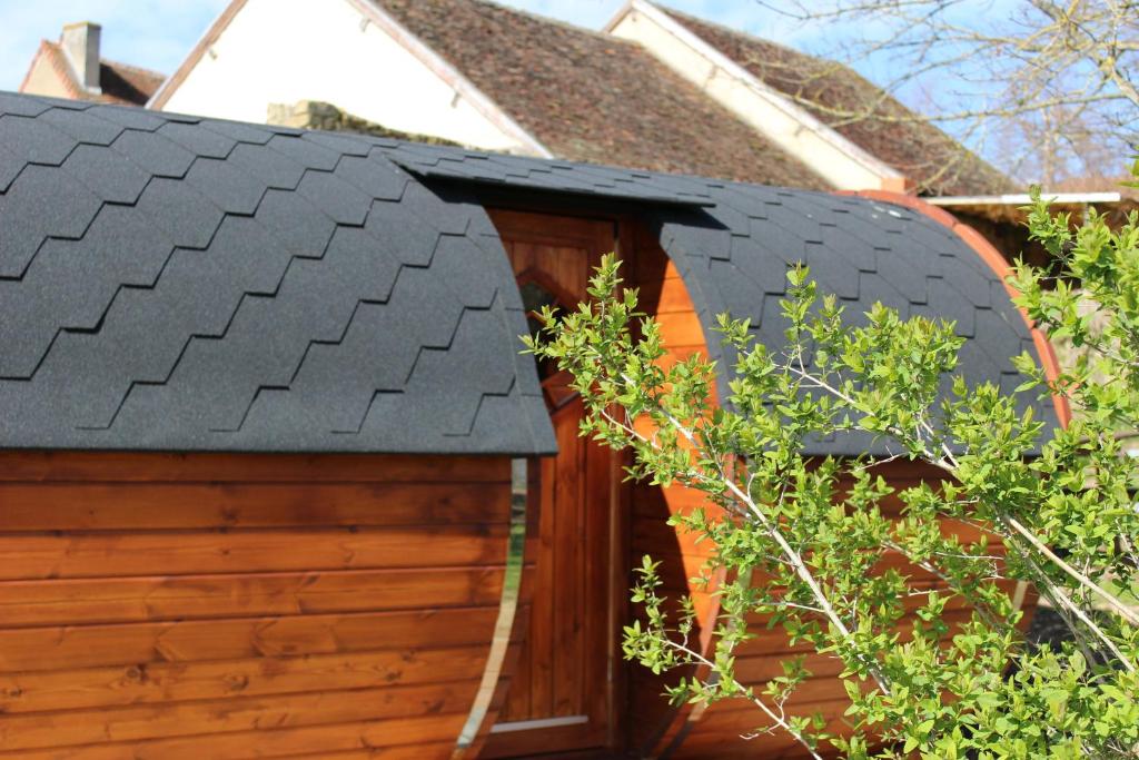 un garage en bois avec un toit noir dans l'établissement Domaine des Marguerites, à Baron
