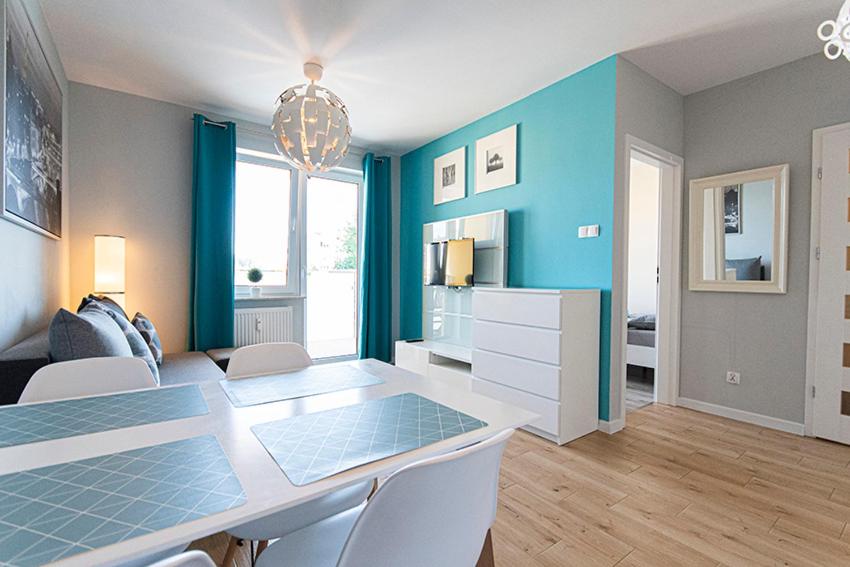 a dining room with a table and blue walls at Apartament SUNtorini in Kołobrzeg