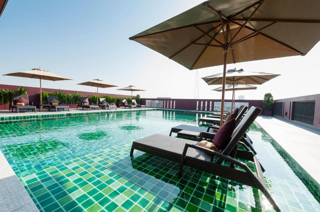 a swimming pool with chairs and umbrellas on a building at Casa Nithra - SHA Extra Plus in Bangkok