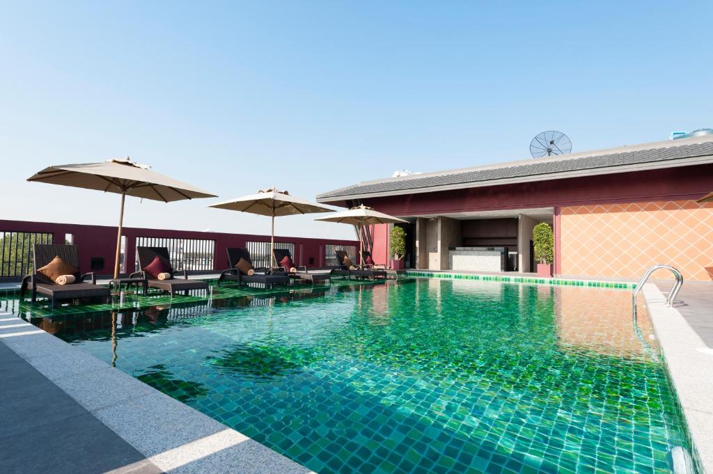 A rooftop pool surrounded by loungers, umbrellas, and a low pool building.