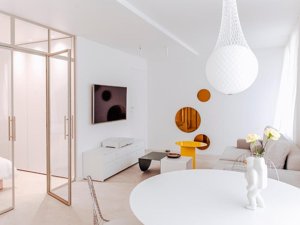 a white living room with a white table and a mirror at Jupiter Silesian Place Apartments in Katowice