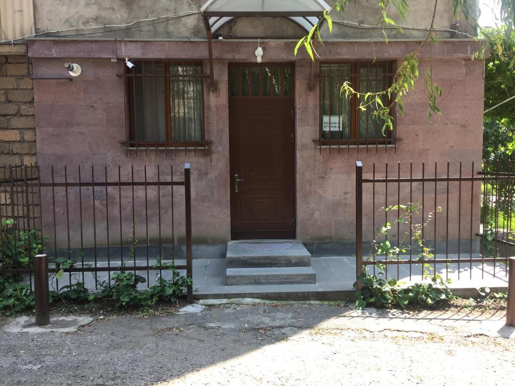a brick house with a brown door and a fence at Apartment on Getapnya 74 in Dilijan