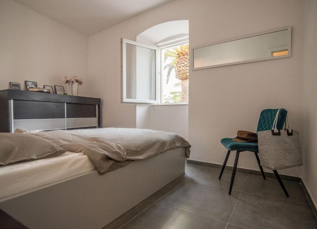 sypialnia z łóżkiem, krzesłem i oknem w obiekcie Apartmani Stones Sutivan I w mieście Sutivan