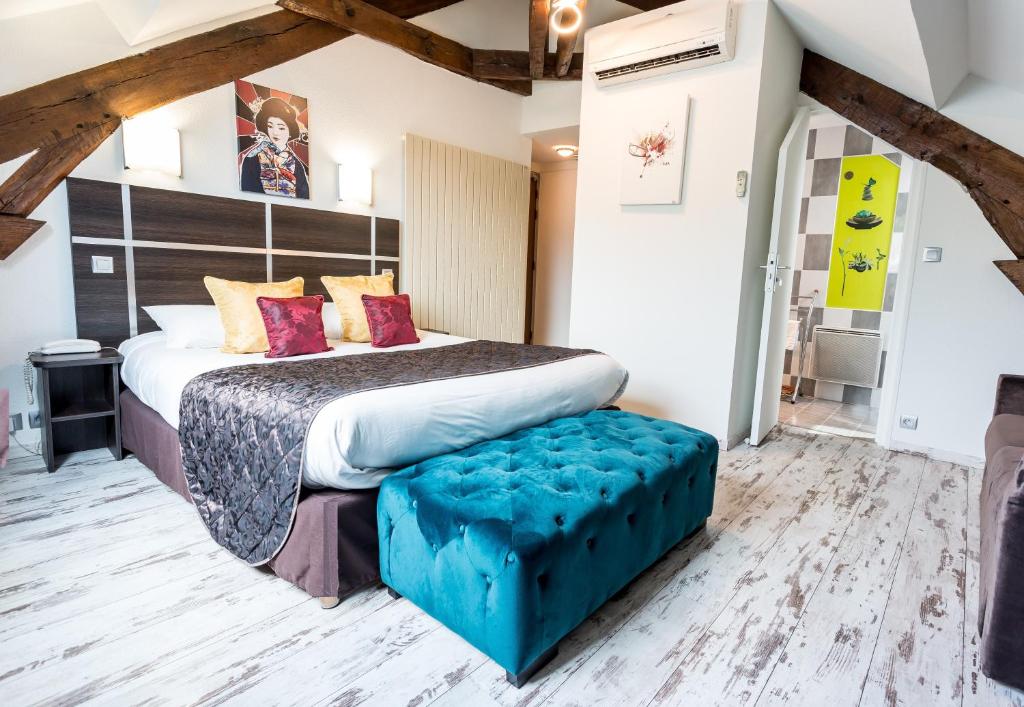 - une chambre avec un grand lit doté d'une ottomane bleue dans l'établissement Hotel Le Centre, à Gramat
