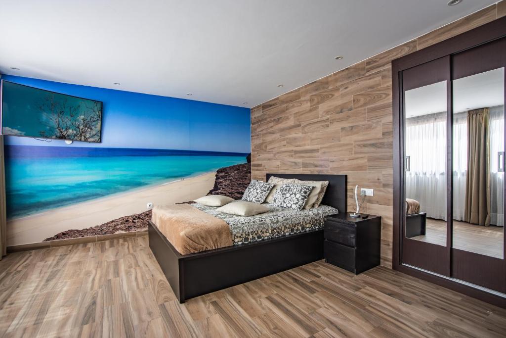 ein Schlafzimmer mit einem Bett und einem Gemälde eines Strandes in der Unterkunft Suite del Mar 4 Jandia in Playa Jandia