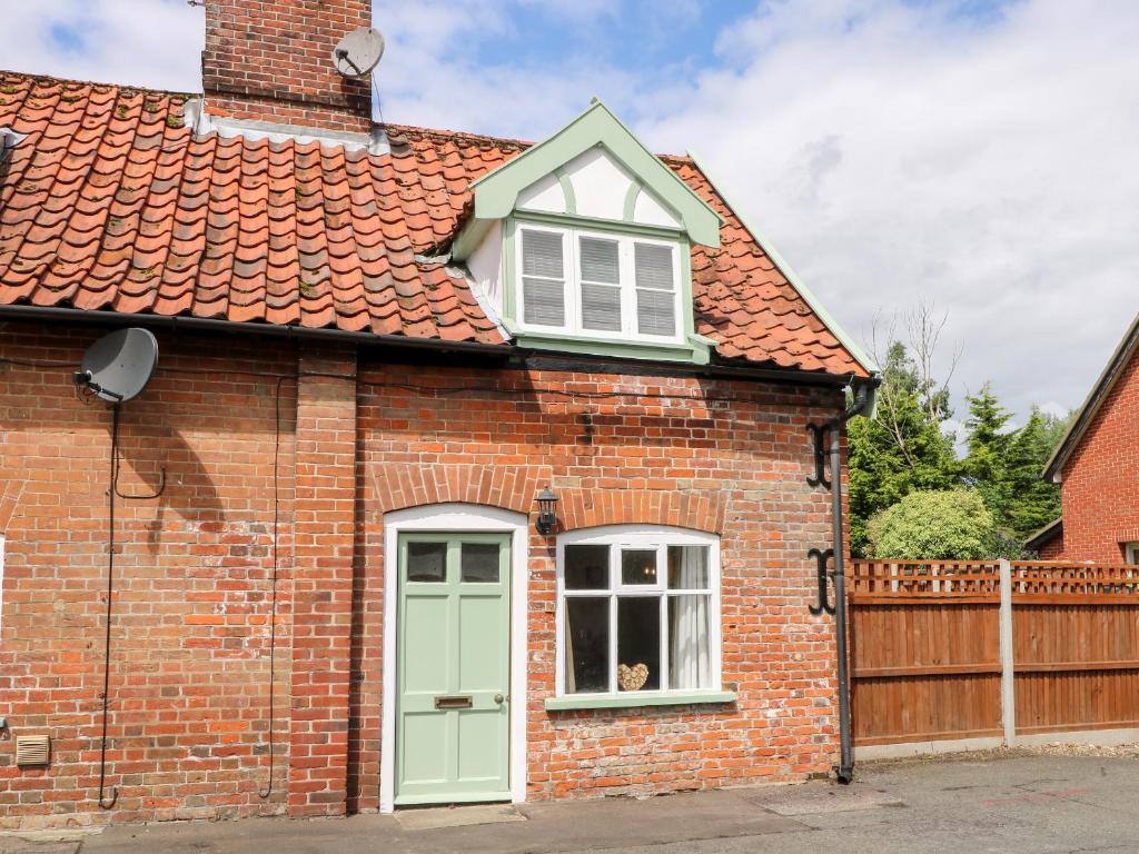una casa in mattoni rossi con una porta verde di Bridge End Cottage a Norwich