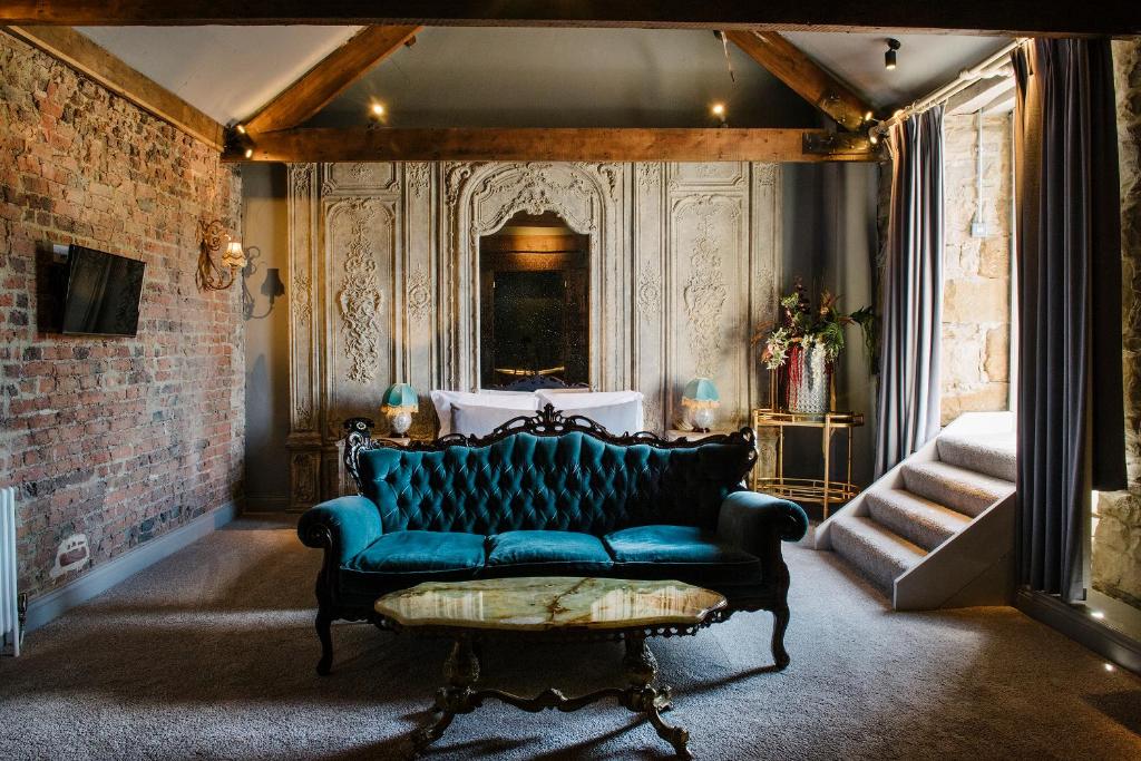 a blue couch in a room with a staircase at Le Petit Chateau & William de Percy in Otterburn