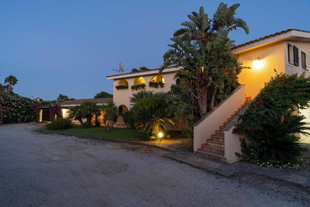 a house with a palm tree next to a driveway at Porto Giunco Residence in Villasimius