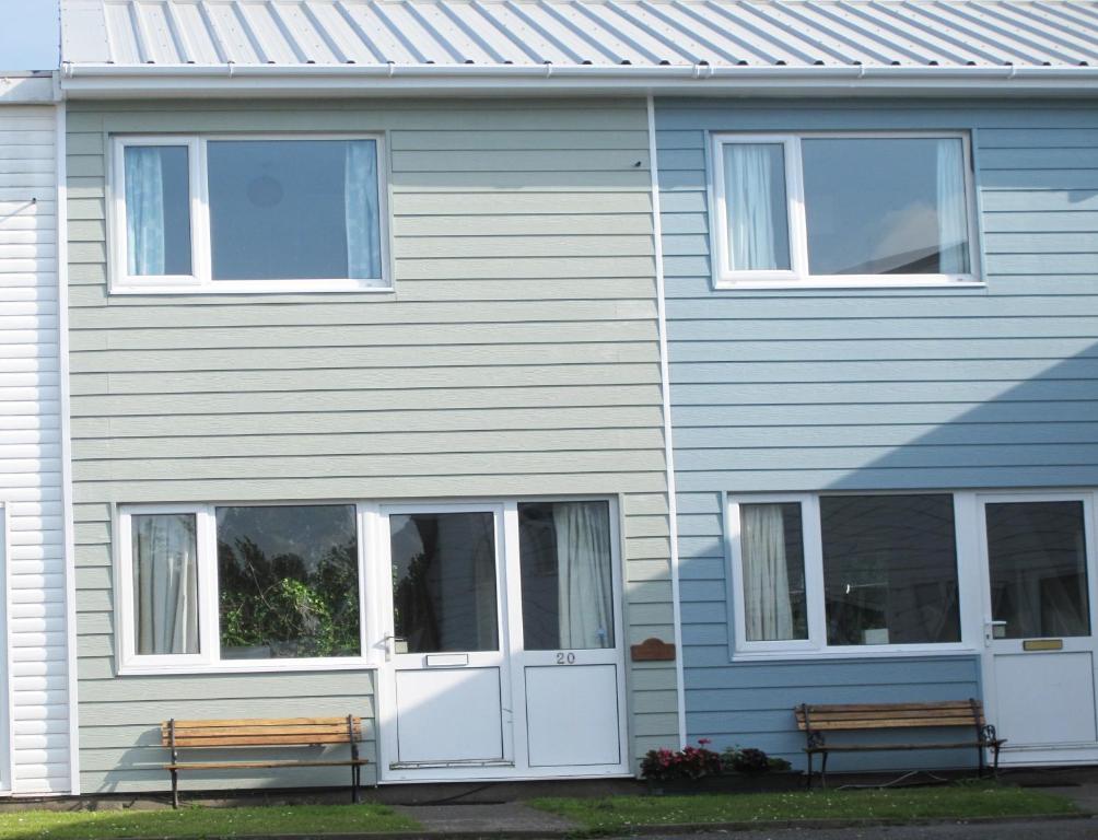 a blue house with two benches in front of it at Freshwater Bay Holiday Cottages in Pembroke