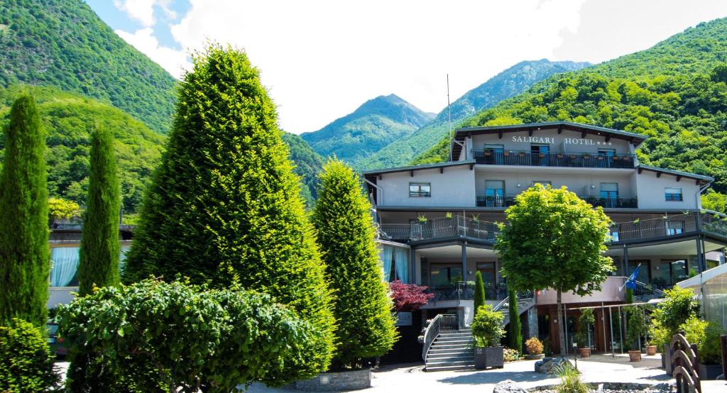 un bâtiment avec des arbres devant une montagne dans l'établissement Hotel Saligari, à Verceia